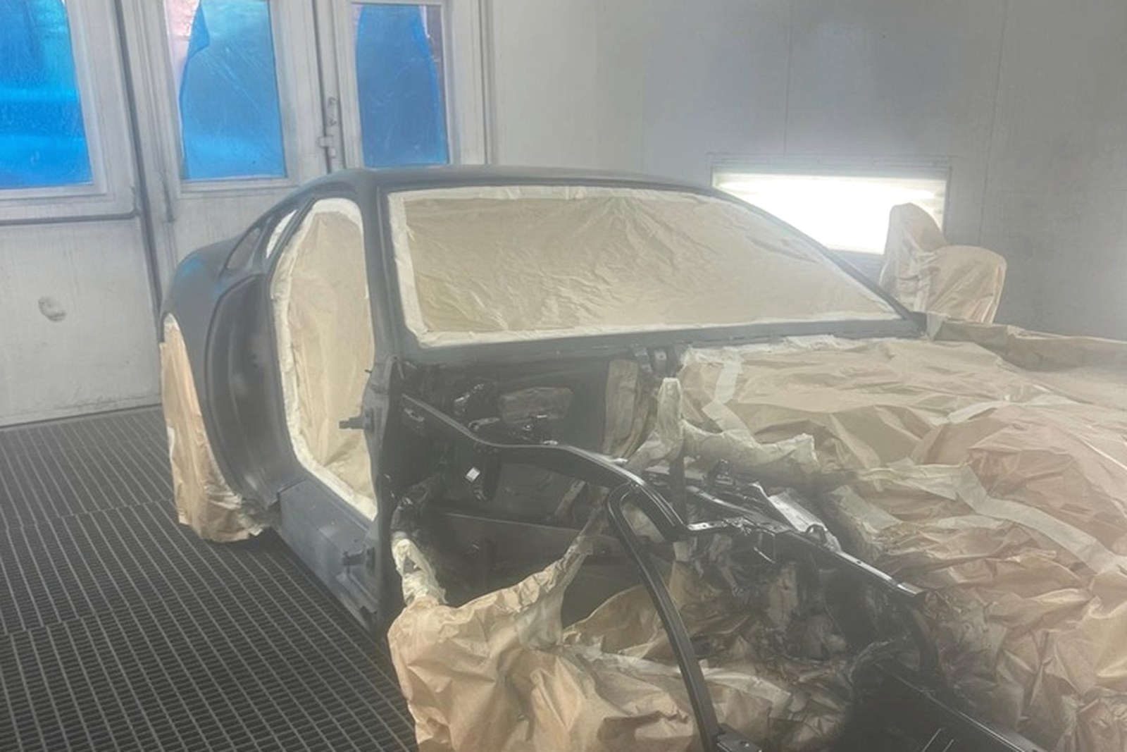 Karoseria Ferrari 812 Superfast zamaskowana w kabinie lakierniczej przed lakierowaniem.