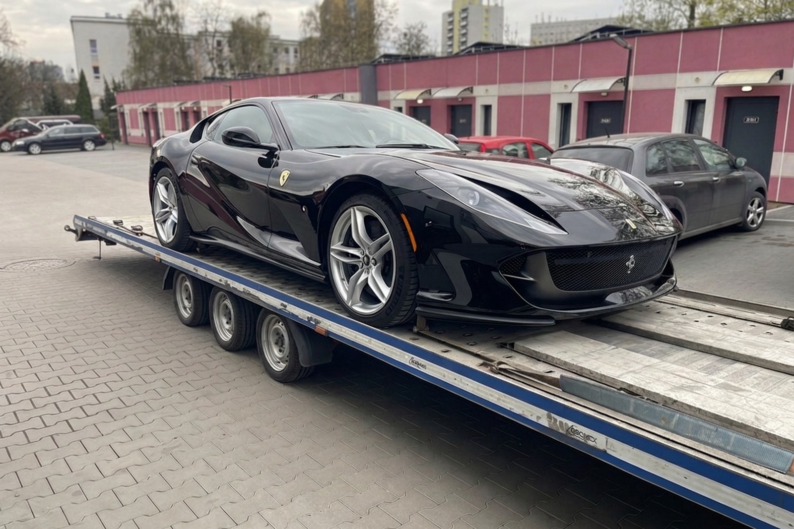 Ukończone Ferrari 812 Superfast zabezpieczone na lawecie, gotowe do transportu po renowacji.