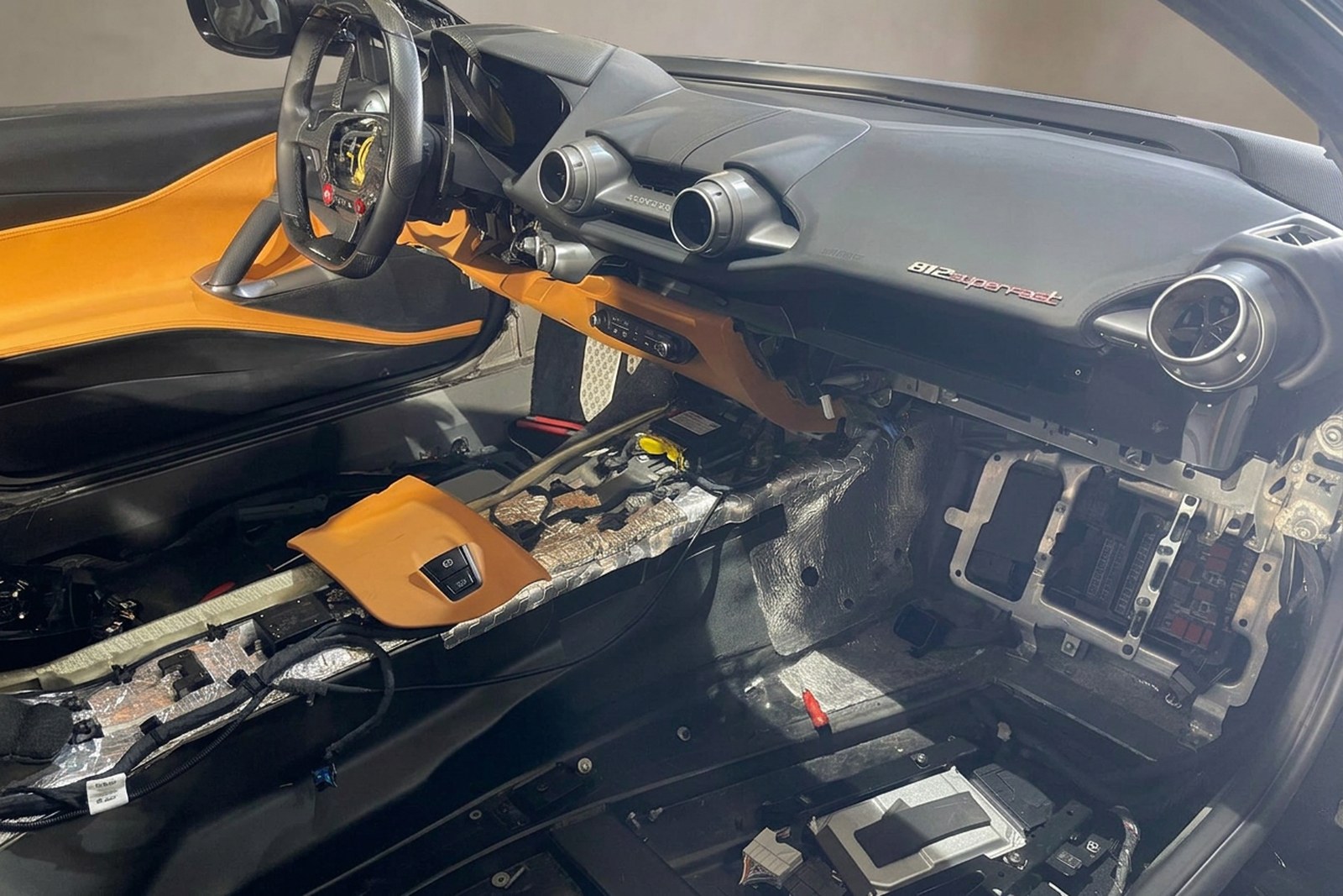 Ponowny montaż wnętrza Ferrari 812 Superfast z tablicą rozdzielczą, kierownicą i jasnobrązową tapicerką.