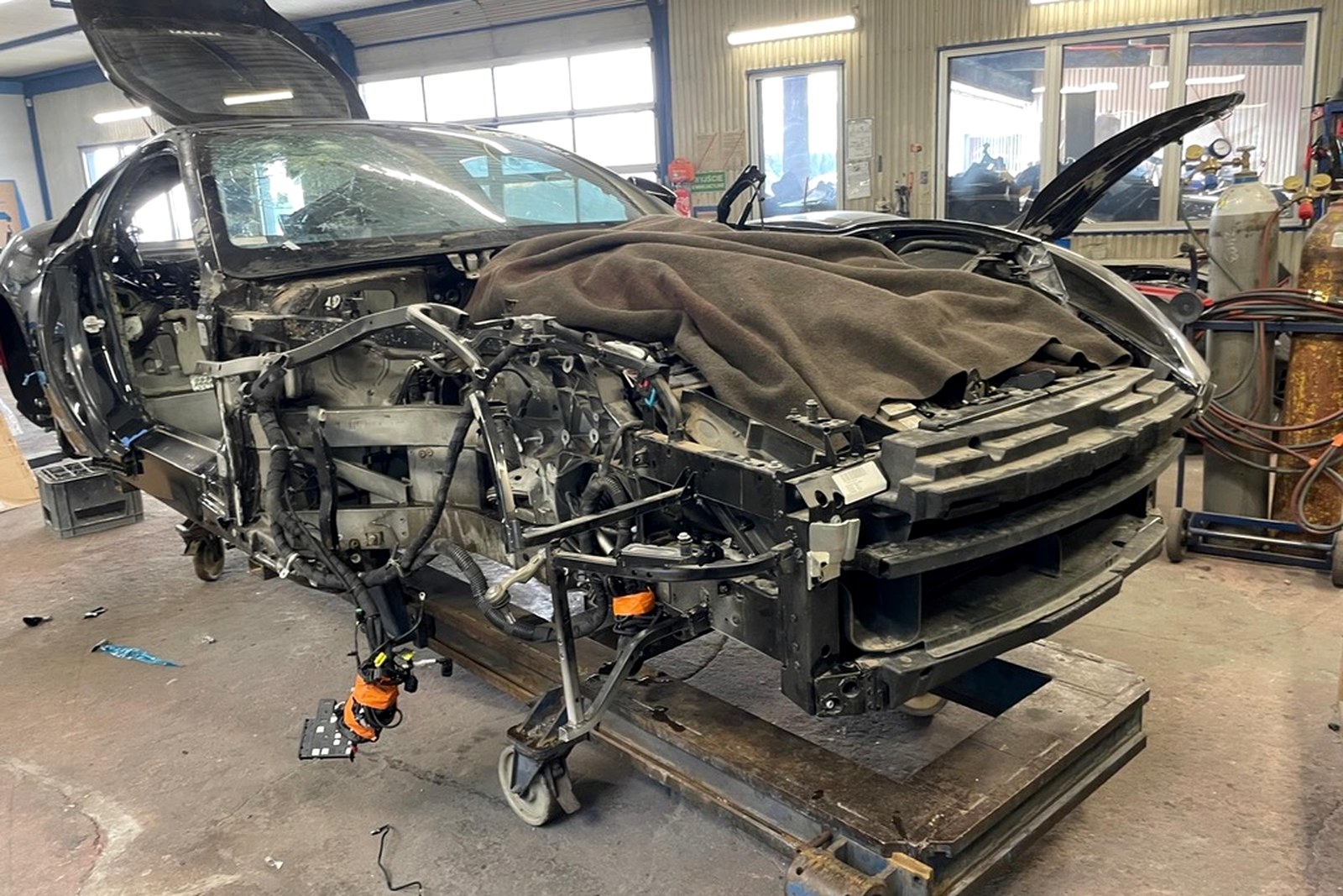 Rozebrana karoseria Ferrari 812 Superfast na stanowisku warsztatowym z otwartą strefą przednią.